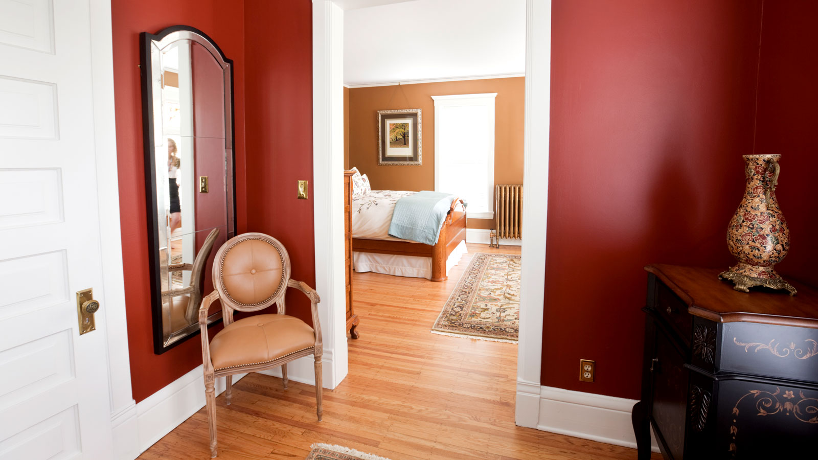 Period home doorway with wooden floor, burgundy walls and white decorative skirting boards