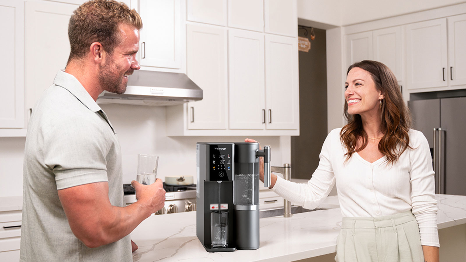Man and women in white kitchen drinking water from Waterdrop Filter hot and cold system