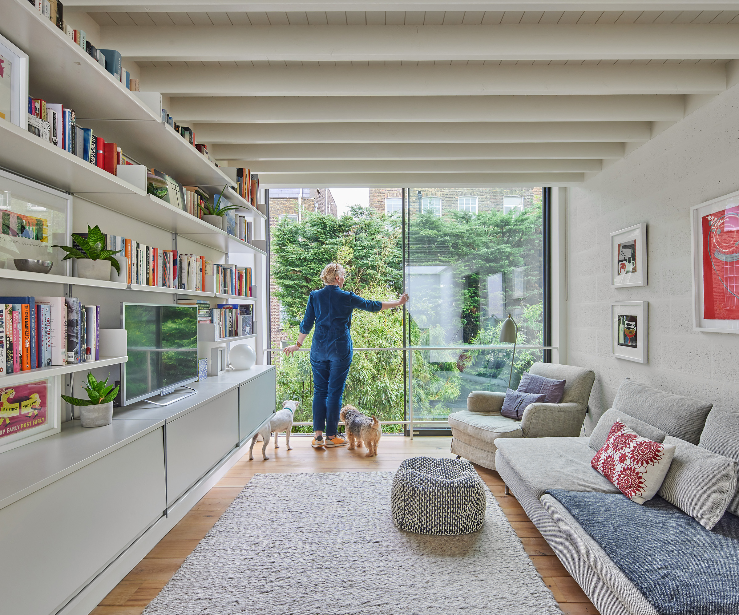A homeowner standing at her floor to ceiling sliding glass doors in her living room with two dogs